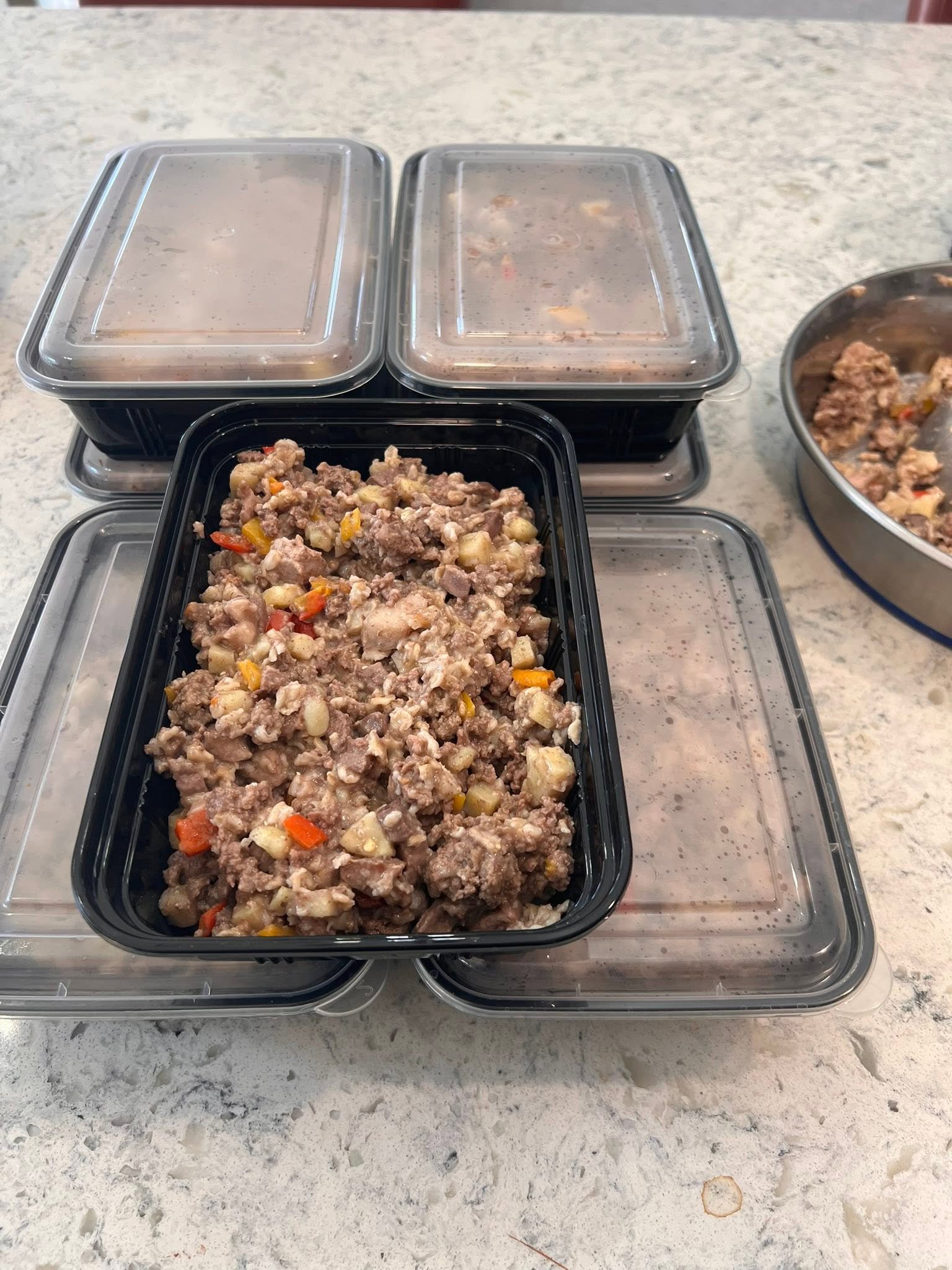 Prepared beef mixture portioned into black containers with clear lids