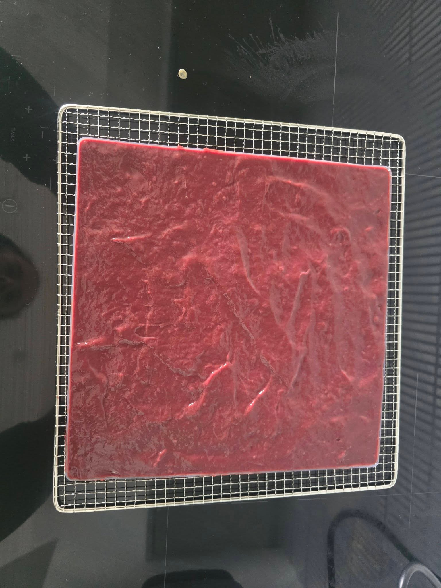 A smooth reddish mixture spread in a rectangular tray on a wire rack