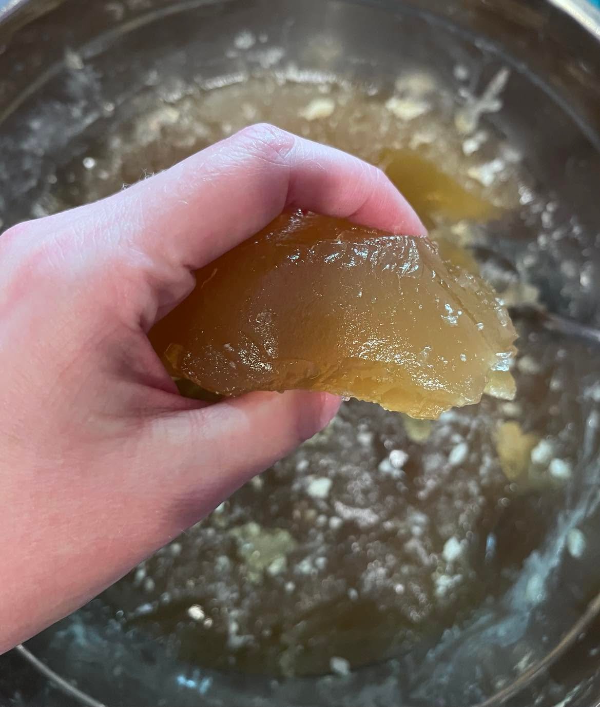 A piece of chilled gelatinous broth held above a bowl