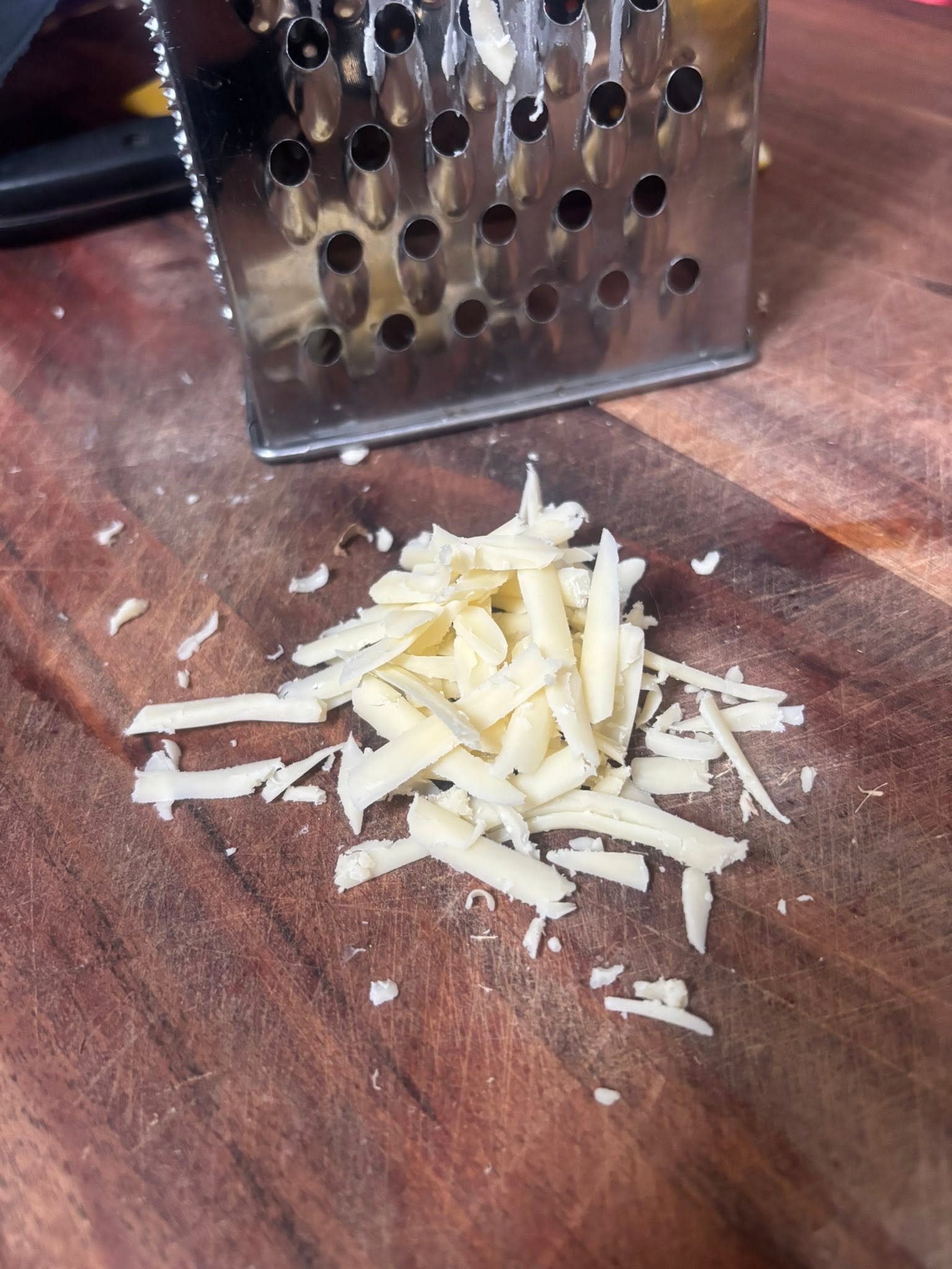Grated cheese beside a box grater