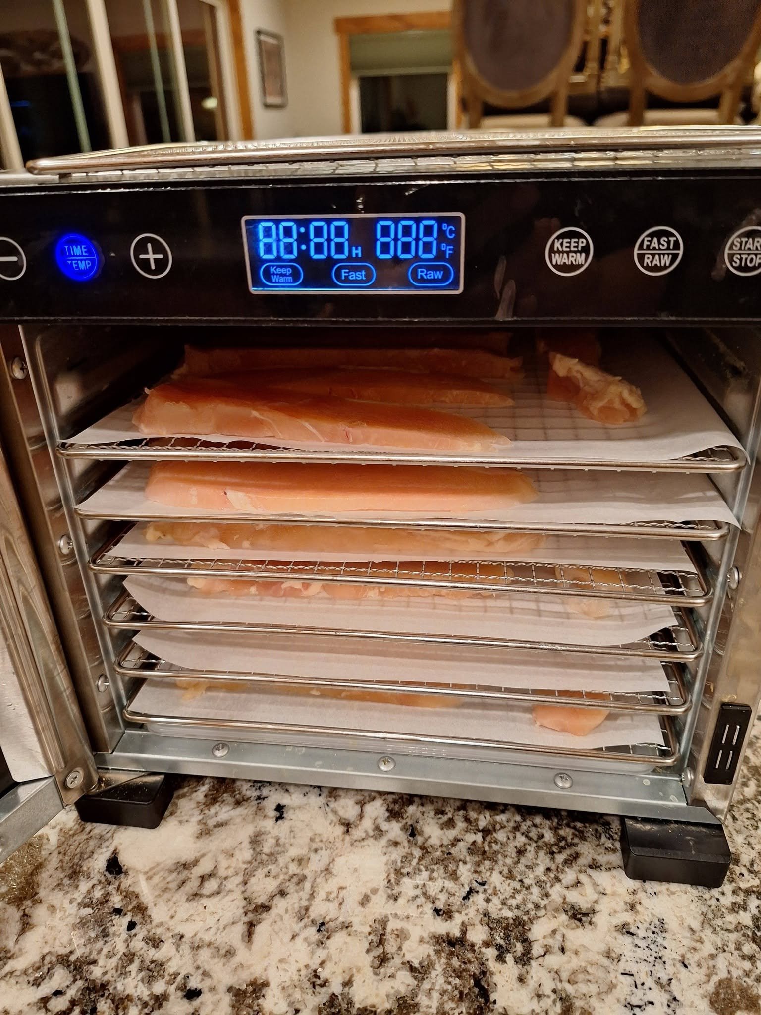 Trays of chicken strips inside a dehydrator