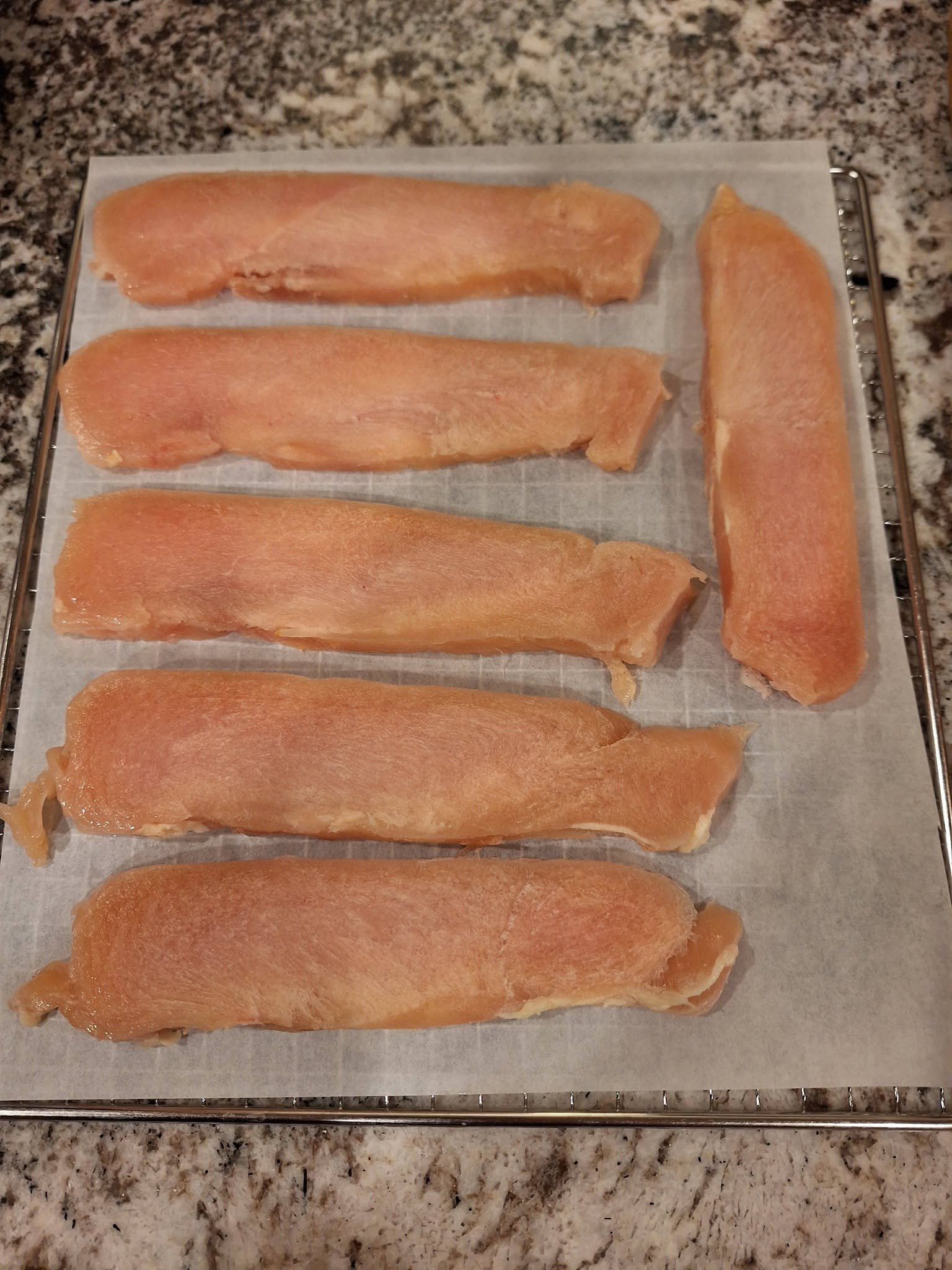 Chicken strips arranged separately on a lined tray