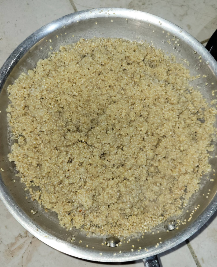 Cooked quinoa spread in a metal pan